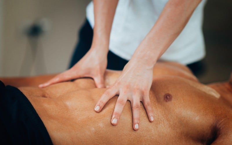 physical therapist massaging sportsman stomach