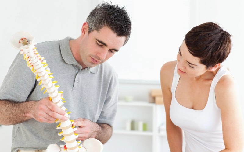 chiropractor and patient looking at a model of a spine