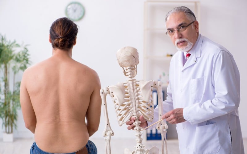 young back injured man visiting experienced male doctor