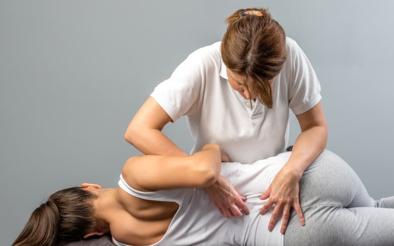 female therapist doing osteopathic spine treatment on patient